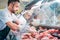 shop assistant in apron assorting fresh raw meat