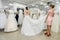 Shop assistant helps bride with wedding dress in boutique