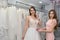 Shop assistant helps bride with wedding dress in boutique