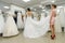 Shop assistant helps bride with wedding dress in boutique