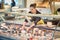 Shop clerk woman sorting cheese in the supermarket display