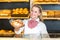 Shopkeeper in bakery presenting loaf of bread to client