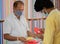 Shopkeeper selling masks to buyer, while both wearing medical mask to protect from coronavirus or covid-19 pandemic -