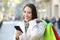 Shopper holding a phone and shopping bags in winter