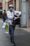 Shopper wearing a face mask walking down a sidewalk pavement