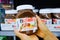 Shoppers hand holding a plastic jar of nutella brand hazelnut spread with cocoa for sale