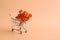 Shopping cart with a bouquet of roses on a pastel pink background. Creative modern minimal composition. Selective focus, copy