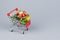 Shopping cart with christmas tree and miniature gift boxes on gray background. Christmas and New Year shopping time background