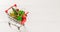 Shopping cart with christmas tree and miniature gift boxes on white wooden table. Christmas and New Year shopping time web banner