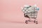Shopping cart loaded with pills on a pink background. The concept of medicine and the sale of drugs. Copy space