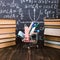 Shopping cart with school supplies, on the table with books against the background of a chalkboard. Concept back to school