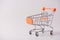 Shopping concept. Close up photo of small push cart with orange elements isolated over gray background with copy blank space