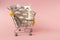 Shopping grocery cart with medicament, tablet, spray, thermometer on pink background. Concept of healthy care, business, shopping