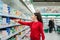Shopping. Portrait of a young woman choosing dairy products in a supermarket refrigerator. Side view. The concept of shopping and