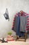 Shopping and style concept - clothes rack with trendy striped pants and plaid, shoes, bag on wooden floor and grey concrete