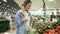 Shopping in the supermarket. Young woman in casual in vegetables department. Selecting fresh cucumbers. Puts them into