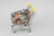 Shopping trolley filled with loose change, british penny coins. Overspending and cost of living concept