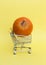 Shopping trolley with pumpkin on pastel yellow background. Vertical shot, copy space. Shopping of vegetarian diet