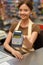Daily Shopping. Young cashier woman at the supermarket offering credit card reader close-up blurred background smiling