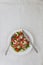 Shopska salad in a white plate on a white tablecloth. The concep