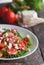 Shopska salad in a white plate on a wooden background, a number