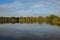 Shore of a lake at sunset with trees and the sky casted in the water