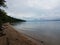 Shore of river with rocks, sand, wood, and shells