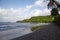 Shore of a tropical island with low tides surrounded by bright green hills covered by trees