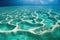 Shore underwater reefs in blue ocean under sky and clouds seascape.