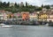Shoreline of Menaggio on Lake Como with European flags and colorful buildings.