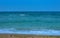 Shoreline on sandy beach, watery waves on the Black Sea during a windy summer day with a blue sky