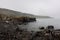 The shoreline with stones near Rubha nam Brathairean Brothers Point in Isle of Skye in Scotland in misty weather