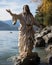 On the shores of a serene lake, a statue of Jesus stands as a beacon of hope and faith, overlooking the tranquil waters