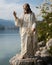 On the shores of a serene lake, a statue of Jesus stands as a beacon of hope and faith, overlooking the tranquil waters