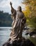 On the shores of a serene lake, a statue of Jesus stands as a beacon of hope and faith, overlooking the tranquil waters