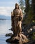 On the shores of a serene lake, a statue of Jesus stands as a beacon of hope and faith, overlooking the tranquil waters