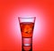 Short drink glass with red liquid and ice cubes