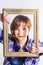 Short haired cute young Woman wearing men`s blue cotton shirt looking through frame, over white background. Close-up studio shot.