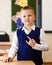 Short-haired eight-year-old handsome schoolboy stands in class in school uniform