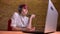 Short-haired girl streamer with manicure and headphones emotionally playing joystick on bricken wall background.