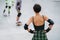 Short-haired woman skater watching others having a go at skatepark.