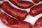 Short thin dry cured sausages on dish, fragment close-up