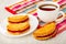 Shortbread cookies with jam in saucer, cup with hot tea on napkin, cookie on wooden table