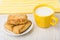 Shortbread cookies with sesame in saucer, milk, yellow napkin