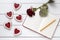 Shortbread heart shaped cookies with empty notebook, pencil and rose flower on white wooden background for Valentines