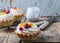 Shortbread tartlets with fruits, berries and protein cream on a rustic wooden background