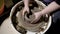 Shot from above of female pottery shaping vase on spinning wheel indoor of workshop.