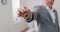 Shot of apartment keys extended on palm of hand toward camera, gray-haired mature man dressed