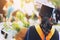 Shot back side young female student in hand holding a bouquet of flowers the graduates of graduation hats