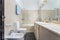 A shot of a bathroom with a marbled sink facing a toilet and a bathtub next to it. Clean looking appearance.